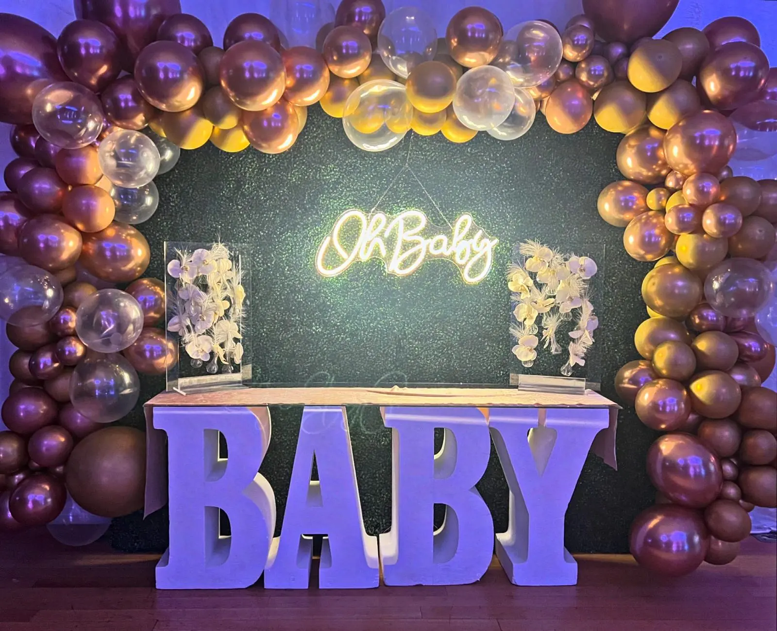 Baby shower backdrop with rose gold balloon arch, neon sign, and marquee letters