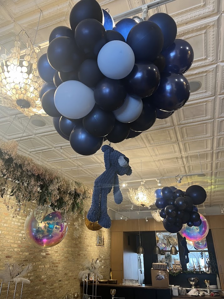 Navy balloon cloud with a hanging bear hovering below the tin ceiling