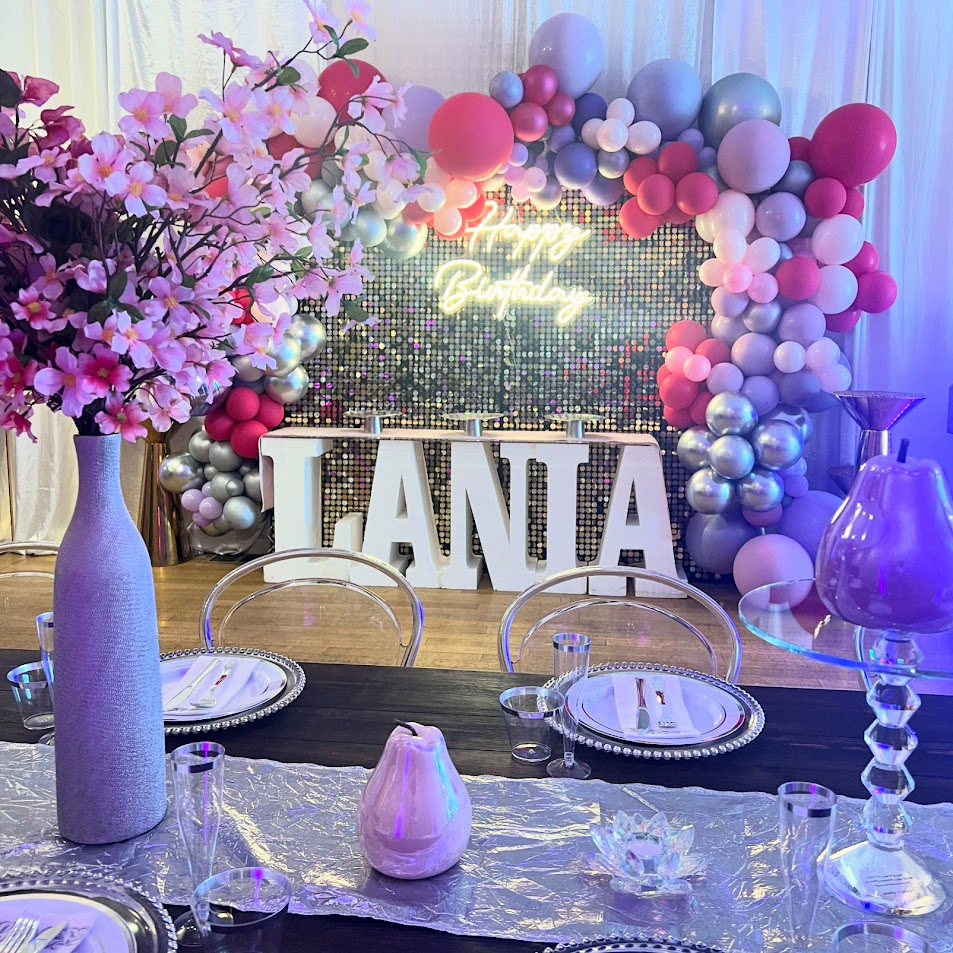 Pink and lavender birthday table with blossom centerpiece and shimmer wall backdrop