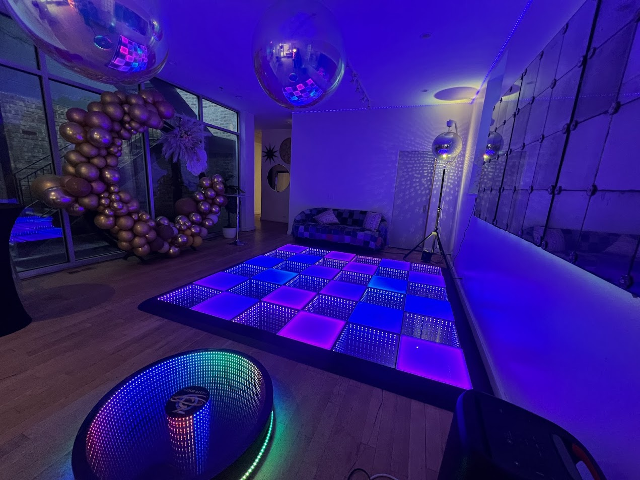 LED dance floor glowing purple and blue with giant disco balls overhead